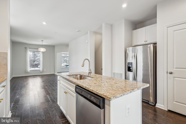 kitchen featuring sink, stainless steel appliances, light stone counters, white cabinets, and a center island with sink