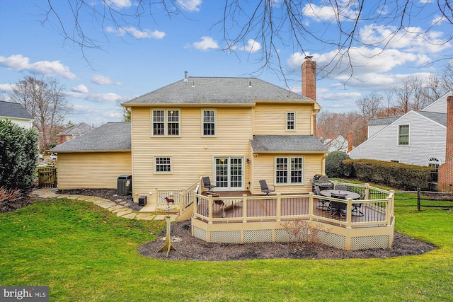 rear view of property with a lawn, central air condition unit, and a deck