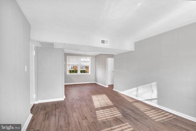 spare room with dark wood-type flooring and a notable chandelier