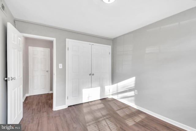 unfurnished bedroom with hardwood / wood-style flooring and a closet