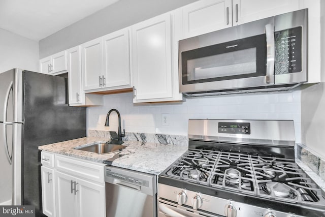 kitchen featuring sink, white cabinets, decorative backsplash, light stone counters, and stainless steel appliances