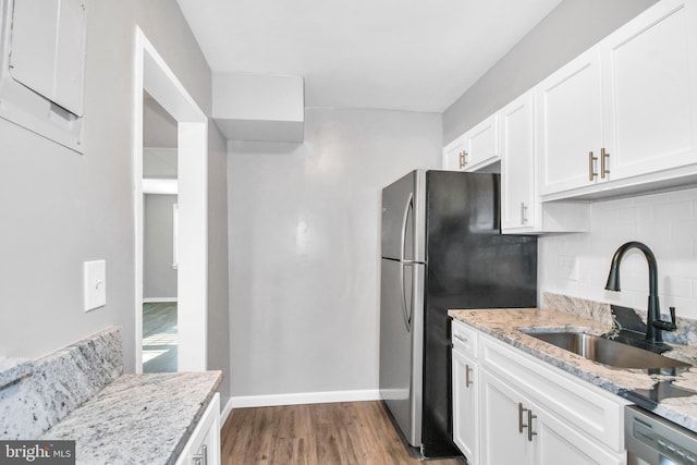 kitchen featuring sink, white cabinetry, light stone counters, wood-type flooring, and appliances with stainless steel finishes