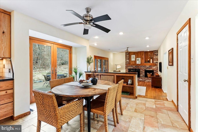 dining area with french doors, recessed lighting, a ceiling fan, a brick fireplace, and baseboards