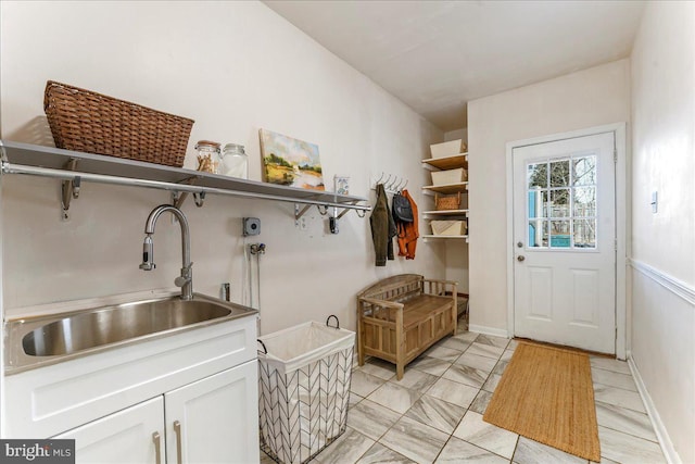 mudroom featuring marble finish floor, a sink, and baseboards