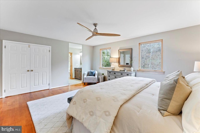 bedroom with light wood-style flooring, a ceiling fan, a closet, and ensuite bathroom