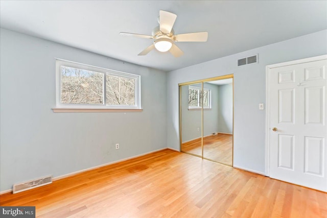 unfurnished bedroom featuring light wood-type flooring, a ceiling fan, visible vents, and a closet