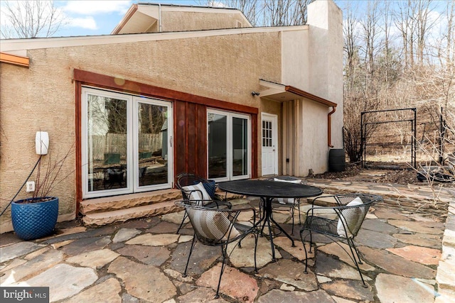 rear view of house with a chimney, stucco siding, outdoor dining space, entry steps, and a patio area