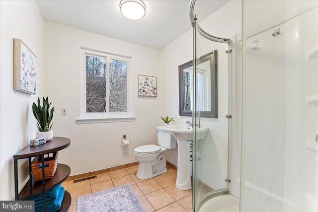 full bath featuring tile patterned flooring, toilet, visible vents, baseboards, and a shower stall