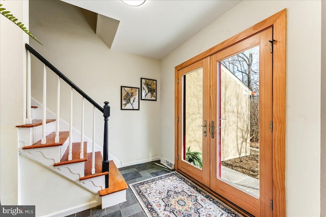 foyer entrance featuring french doors, stone finish flooring, stairway, and baseboards