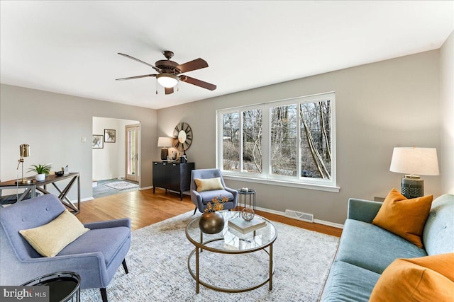 living area with a ceiling fan, baseboards, visible vents, and wood finished floors