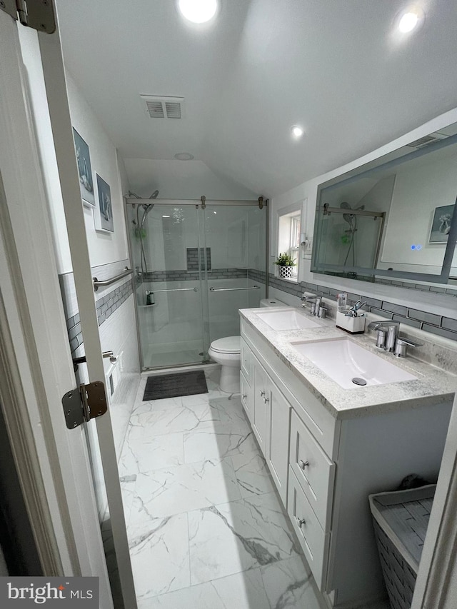 bathroom featuring walk in shower, vanity, toilet, and tile walls