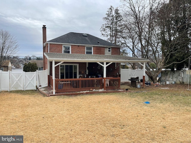 back of property featuring a deck and a lawn