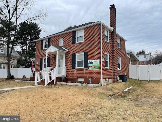 view of front of property with a front lawn and central air condition unit