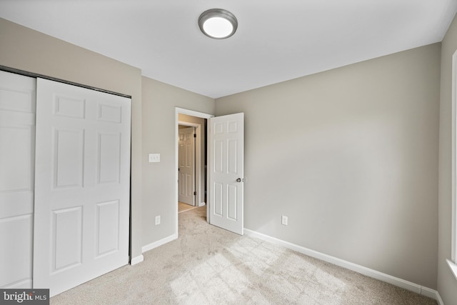 unfurnished bedroom with a closet and light colored carpet