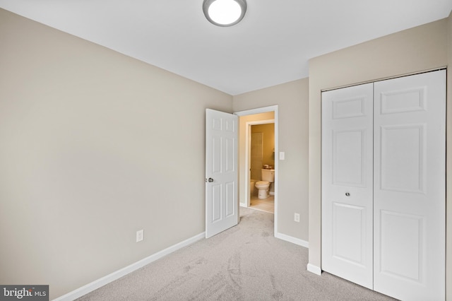 unfurnished bedroom featuring light carpet and a closet