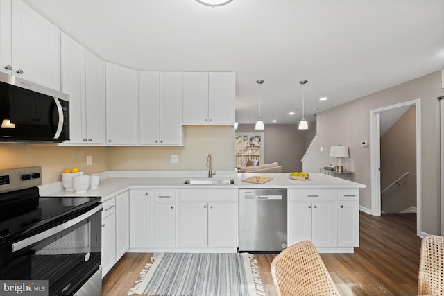 kitchen with appliances with stainless steel finishes, dark wood-type flooring, decorative light fixtures, sink, and white cabinetry