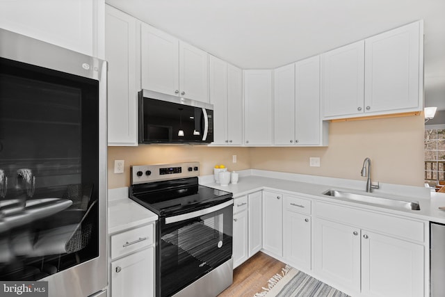 kitchen featuring sink, refrigerator, white cabinetry, electric range, and light hardwood / wood-style floors