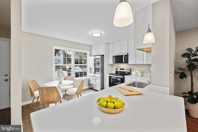 kitchen with appliances with stainless steel finishes, sink, dark hardwood / wood-style flooring, and decorative light fixtures