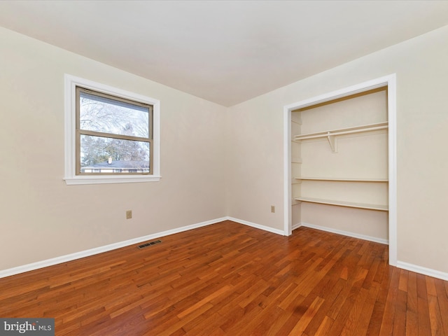 unfurnished bedroom with a closet and dark hardwood / wood-style floors