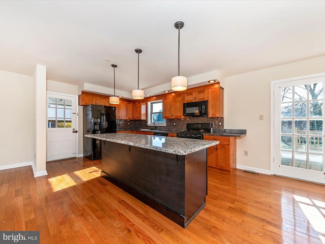 kitchen with decorative light fixtures, a breakfast bar area, backsplash, and black appliances