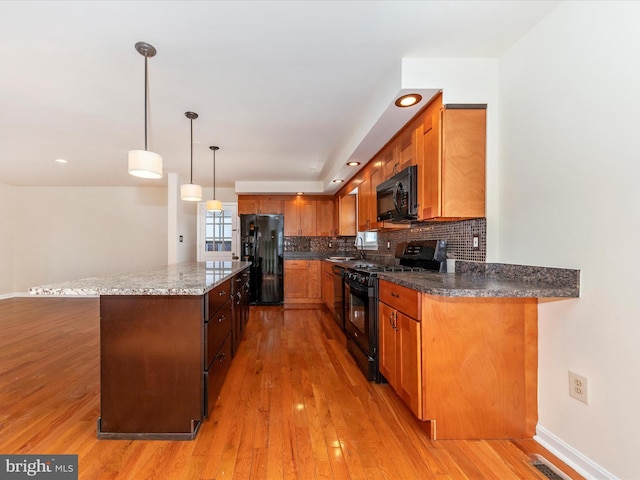 kitchen featuring decorative light fixtures, sink, decorative backsplash, black appliances, and light hardwood / wood-style flooring