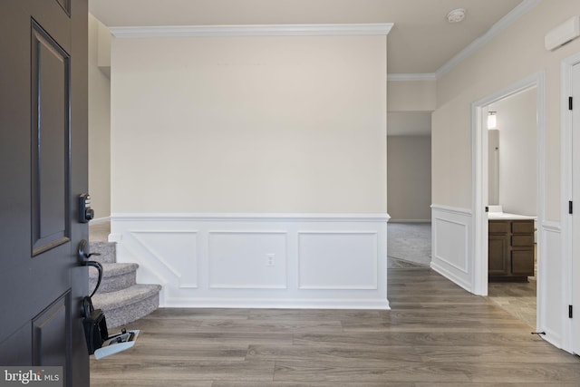 entrance foyer featuring a decorative wall, crown molding, and wood finished floors