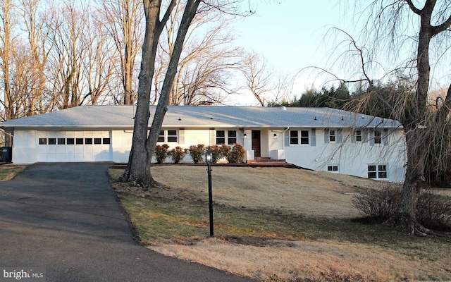 ranch-style house with a garage and a front lawn