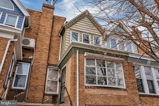 view of property exterior with ac unit, brick siding, and a chimney