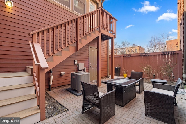 view of patio / terrace featuring an outdoor fire pit, fence, stairway, and cooling unit