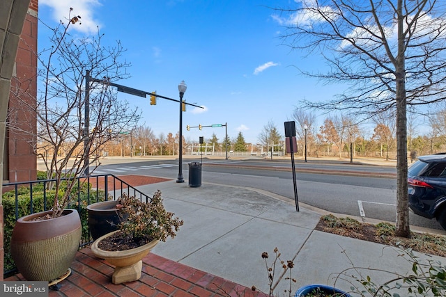 view of street featuring curbs, traffic lights, traffic signs, and sidewalks