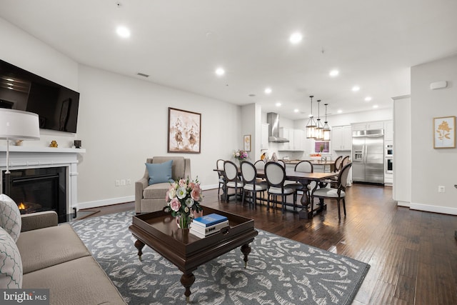 living area with dark wood-style floors, a fireplace with flush hearth, baseboards, and recessed lighting