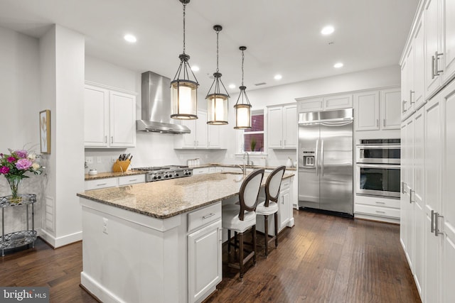 kitchen with stainless steel appliances, wall chimney exhaust hood, dark wood finished floors, and white cabinetry