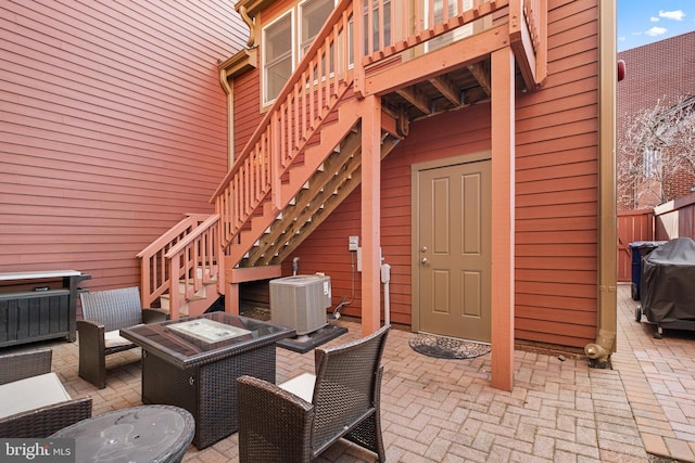 view of patio featuring cooling unit, fence, and stairway