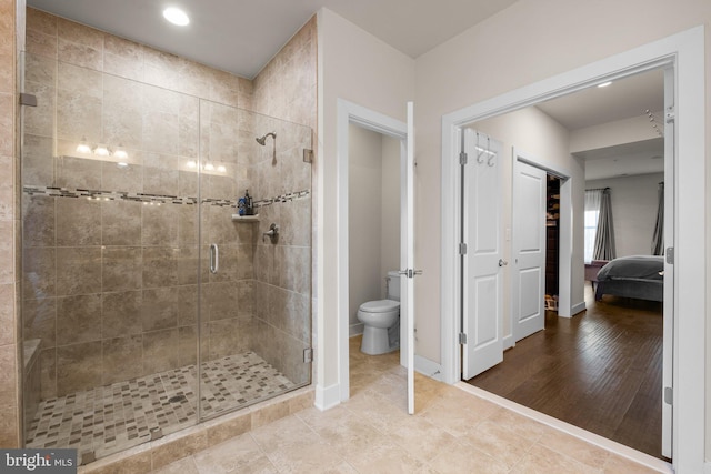 ensuite bathroom featuring toilet, a shower stall, baseboards, and connected bathroom