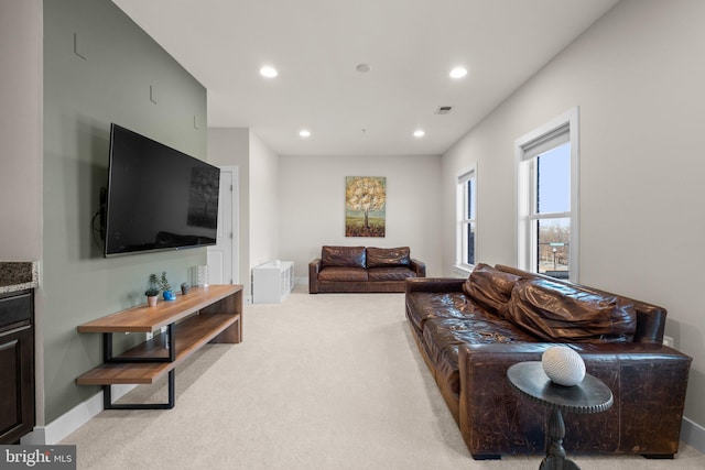 living area with recessed lighting, visible vents, baseboards, and light colored carpet