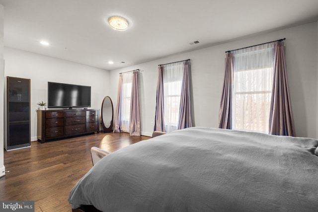 bedroom featuring dark wood-style floors, multiple windows, visible vents, and recessed lighting