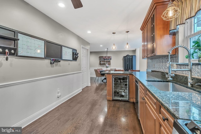 kitchen with decorative light fixtures, glass insert cabinets, brown cabinetry, a sink, and beverage cooler