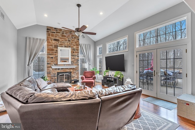 living area with visible vents, light wood-style flooring, french doors, a fireplace, and high vaulted ceiling