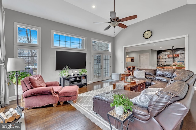 living area with ceiling fan, high vaulted ceiling, wood finished floors, baseboards, and french doors