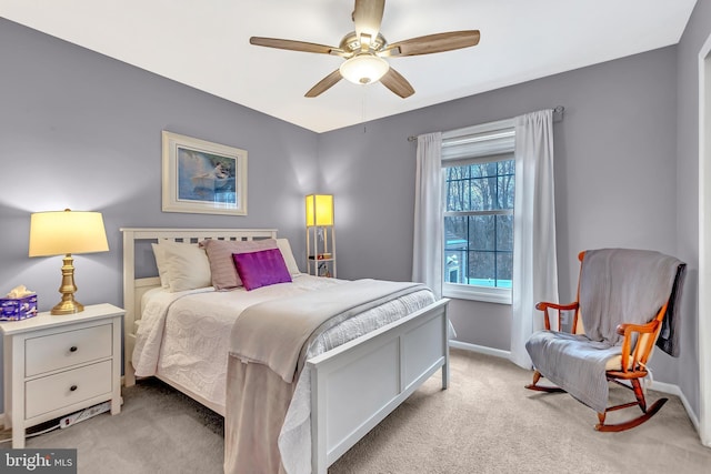 bedroom featuring light carpet, a ceiling fan, and baseboards