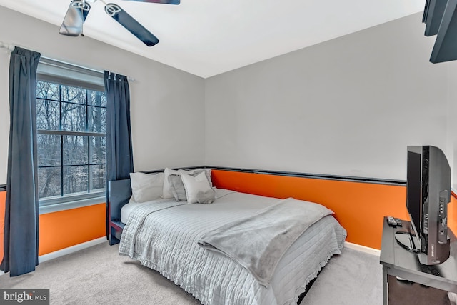 bedroom with ceiling fan, baseboards, and light colored carpet