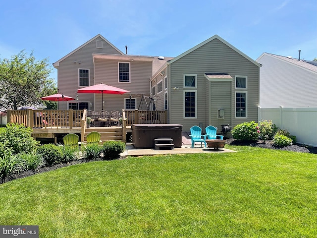 rear view of property featuring a hot tub, a lawn, a patio, fence, and a wooden deck