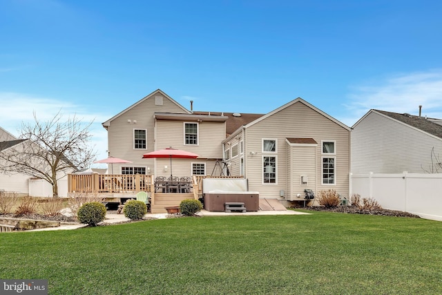 rear view of house with a deck, fence, a hot tub, and a lawn