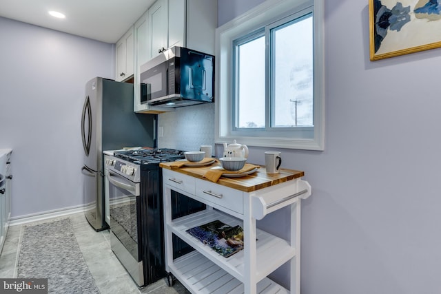 kitchen featuring wooden counters, white cabinets, and appliances with stainless steel finishes