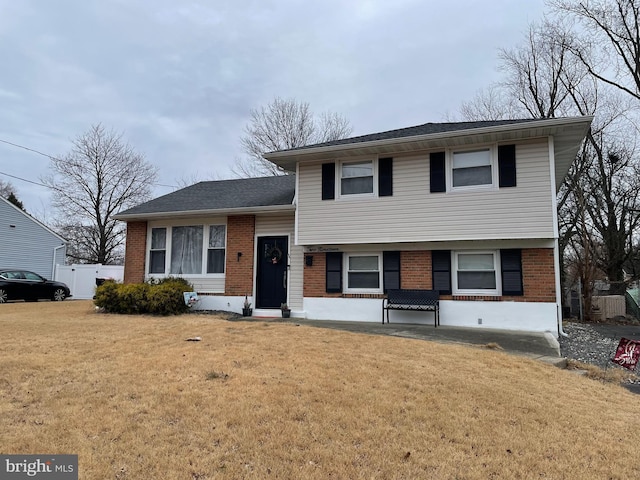 tri-level home with brick siding and a front yard