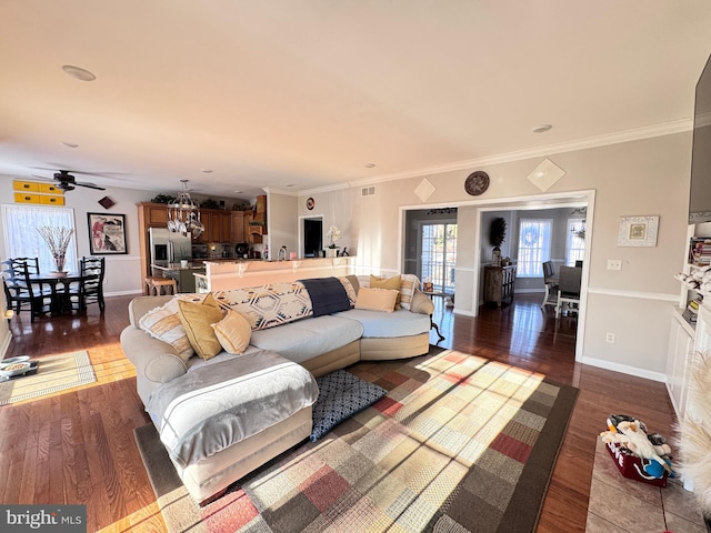 living room featuring dark wood-style flooring, visible vents, crown molding, and baseboards