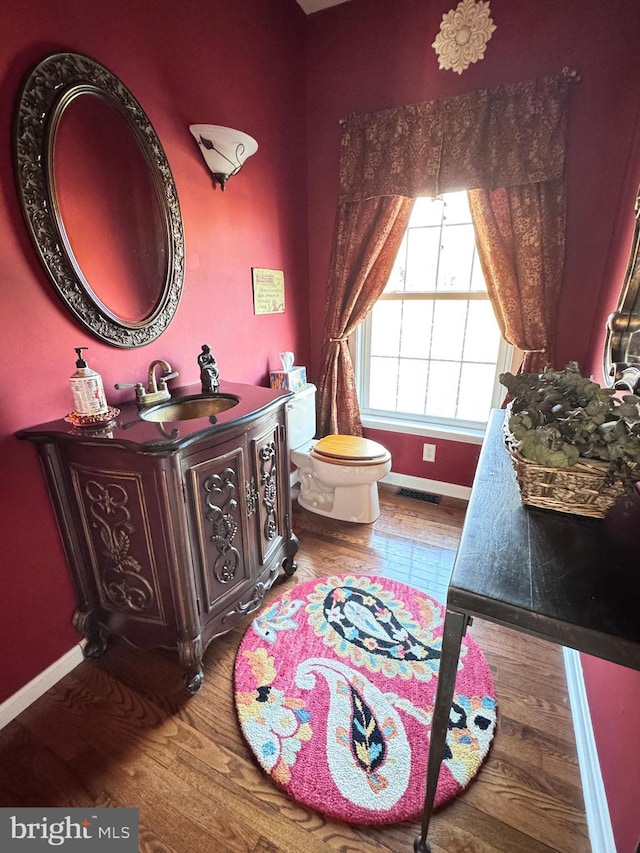 bathroom featuring baseboards, vanity, toilet, and wood finished floors