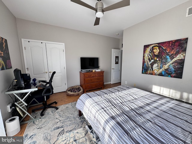 bedroom featuring a ceiling fan, a closet, visible vents, and wood finished floors