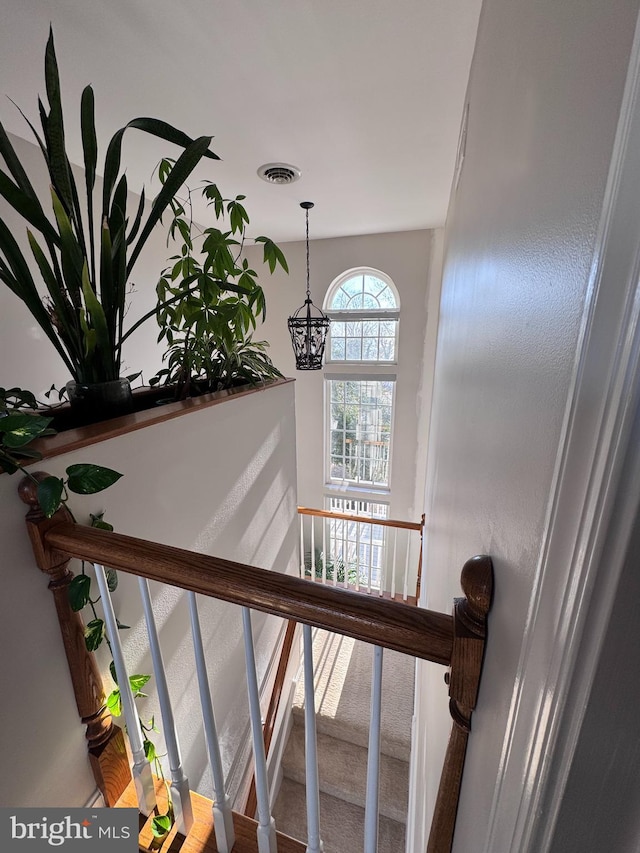 stairway with visible vents and a notable chandelier