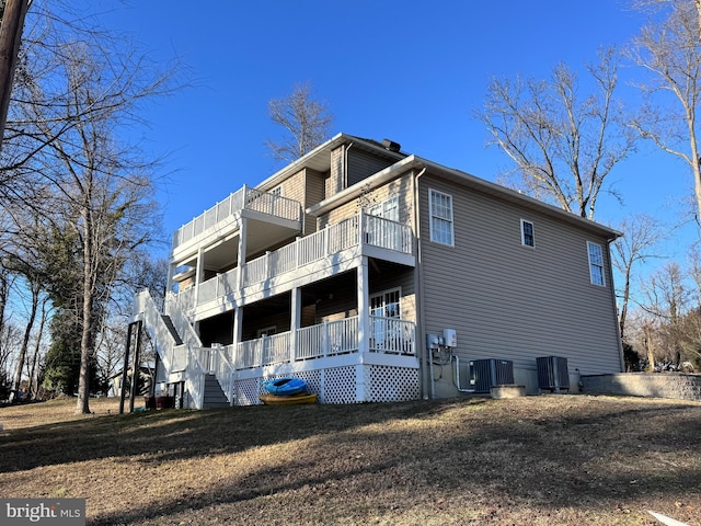 view of side of property with stairway, a balcony, and central air condition unit